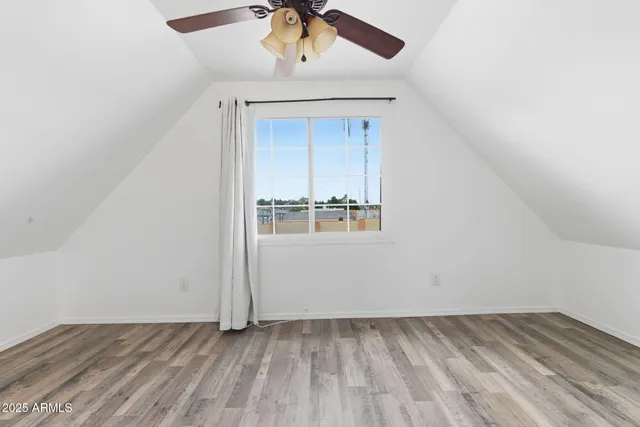 an empty room with a ceiling fan and wooden floor