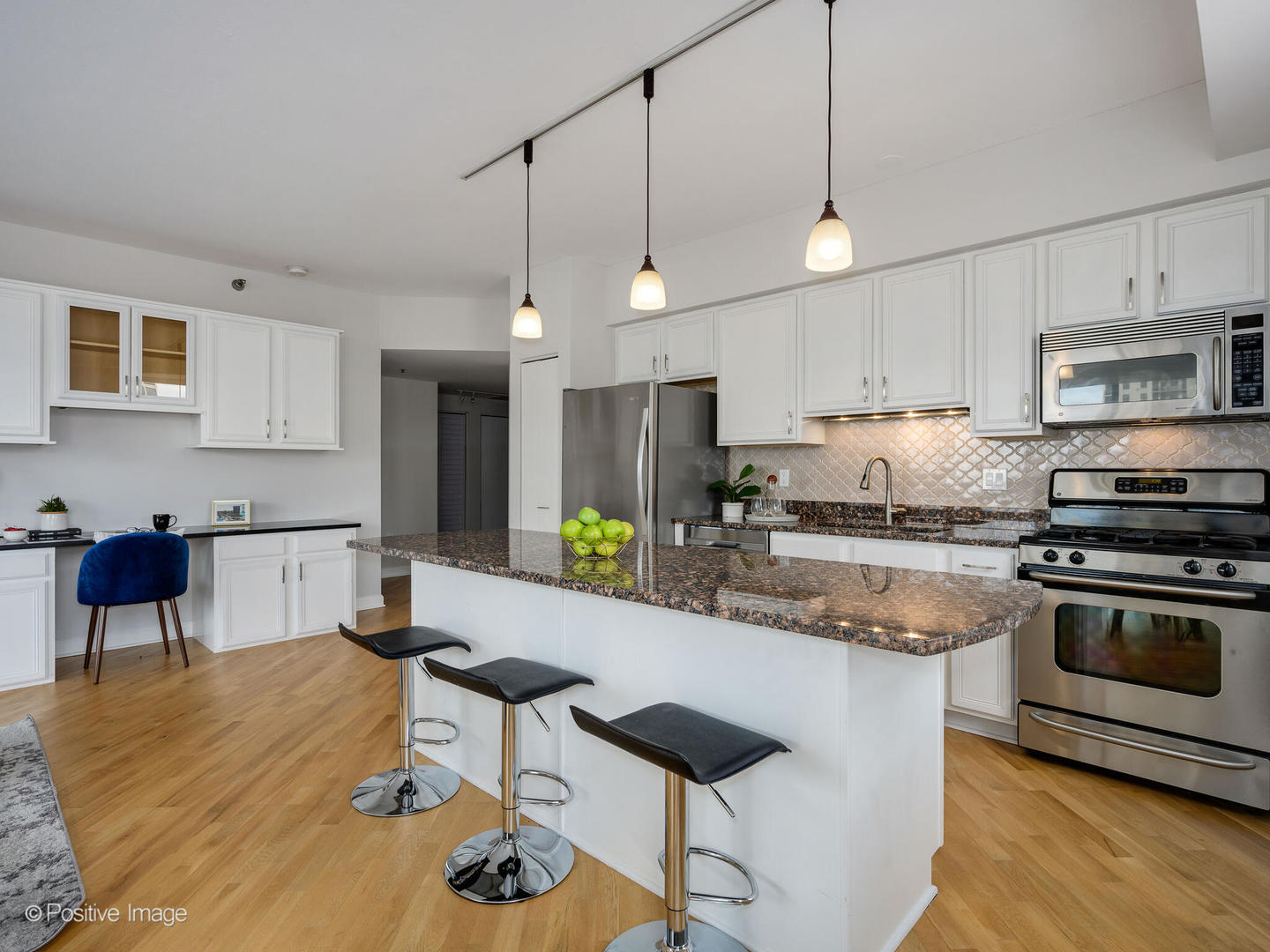 5 East 14th Place, Unit 501 Chicago, IL 60605 - Photo 4 of 26 a kitchen with stainless steel appliances granite countertop a stove a sink a microwave a refrigerator a stove and white cabinets with wooden floor