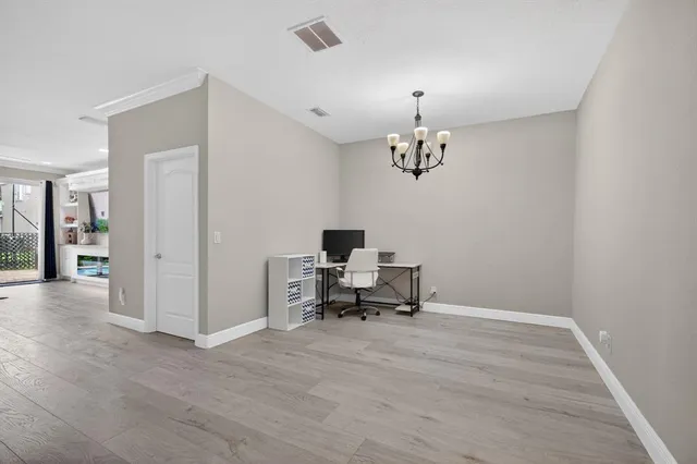 a dining room with wooden floor a chandelier a glass table and chairs