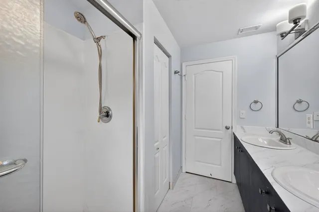 a bathroom with a double vanity sink a mirror and shower