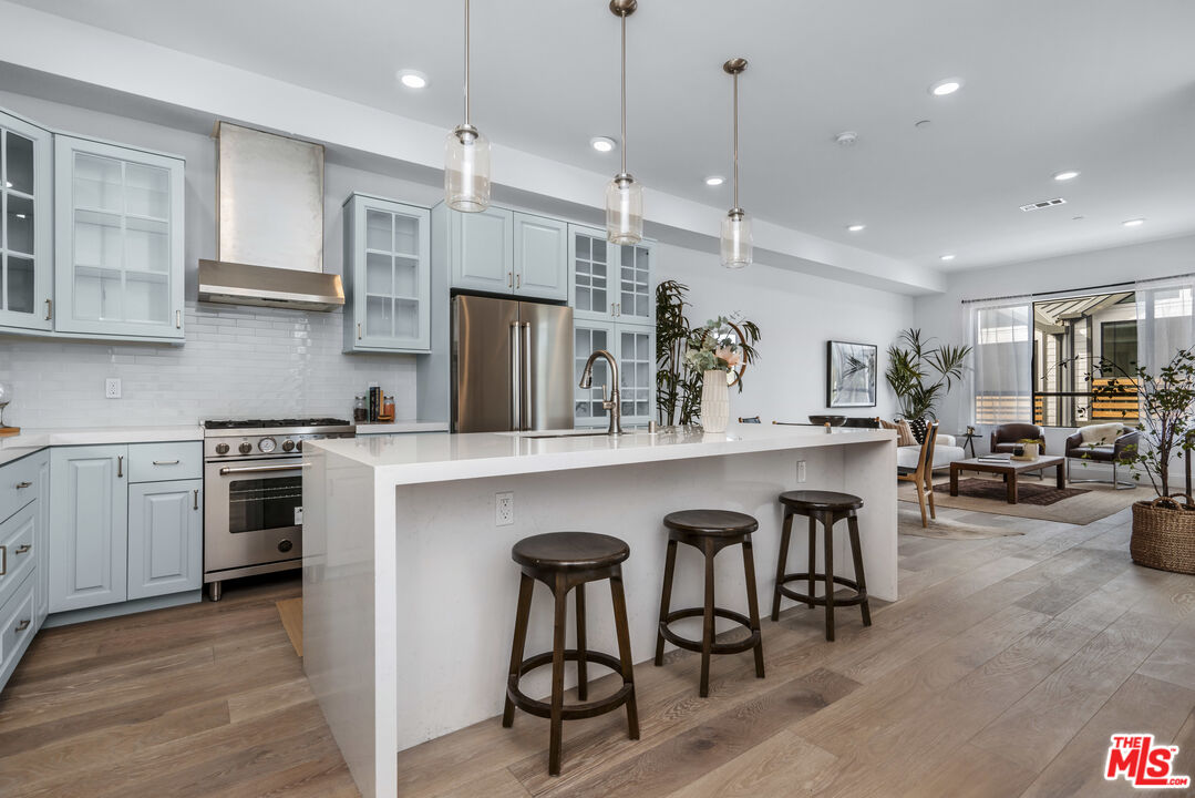 a kitchen with stainless steel appliances granite countertop a stove a sink a oven a dining table and chairs with wooden floor