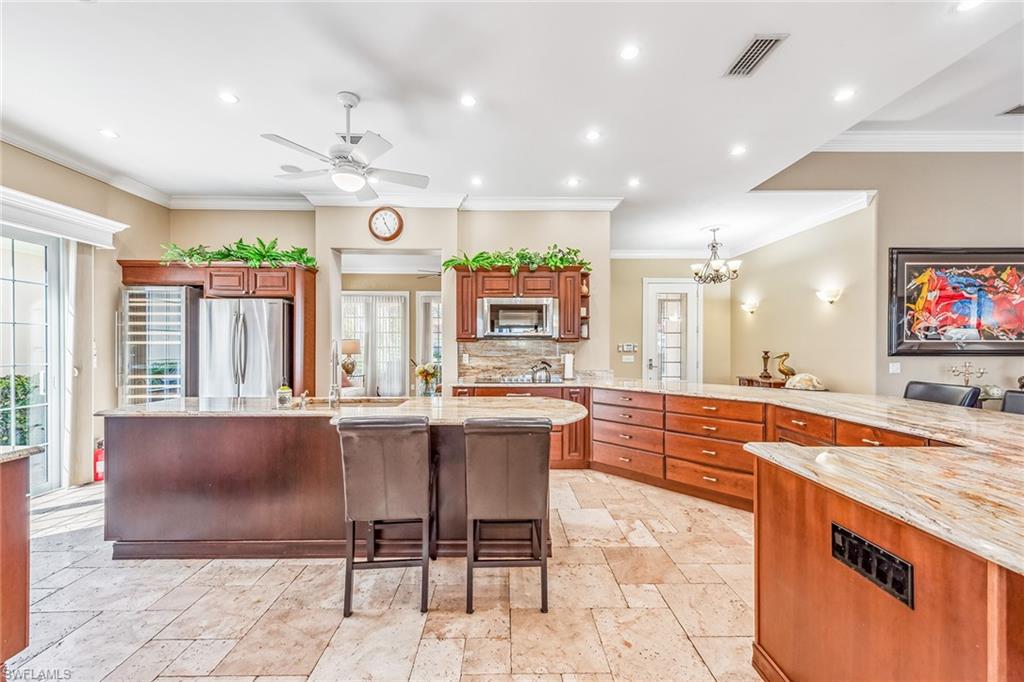 2881 Hatteras Way Naples, FL 34119 - Photo 8 of 32 a large kitchen with granite countertop a large stove a sink and a dining table with chairs