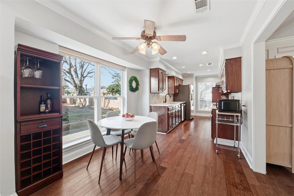 1704 Throwbridge Lane Plano, TX 75023 - Photo 15 of 40 Breakfast area features smooth ceiling with crown molding and a ceiling-mounted fan with light kit. Large window provides natural light, with hardwood flooring extending throughout and direct access to adjacent kitchen and stairway areas.