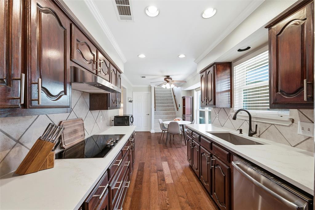 1704 Throwbridge Lane Plano, TX 75023 - Photo 17 of 40 Kitchen features smooth ceiling with crown molding and recessed lighting. Cabinetry extends to the ceiling, paired with quartz countertops and tile backsplash. Appliances include dual electric ovens, electric cooktop, and dishwasher. Pantry provides additional storage, with hardwood flooring extending throughout and direct connection to adjacent breakfast area.