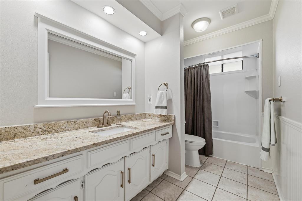 1704 Throwbridge Lane Plano, TX 75023 - Photo 25 of 40 Secondary Bathroom features smooth ceiling with crown molding and recessed lighting. Single-sink vanity includes granite countertop and framed mirror, with tub/shower combination and tile surround. Tile flooring extends throughout the space.
