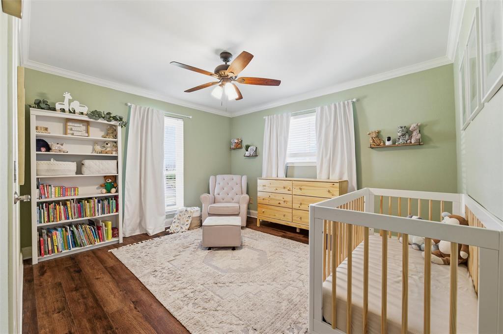 1704 Throwbridge Lane Plano, TX 75023 - Photo 26 of 40 Secondary Bedroom features smooth ceiling with crown molding and ceiling fan with integrated light. Multiple windows provide natural light, with hardwood flooring extending throughout the room.