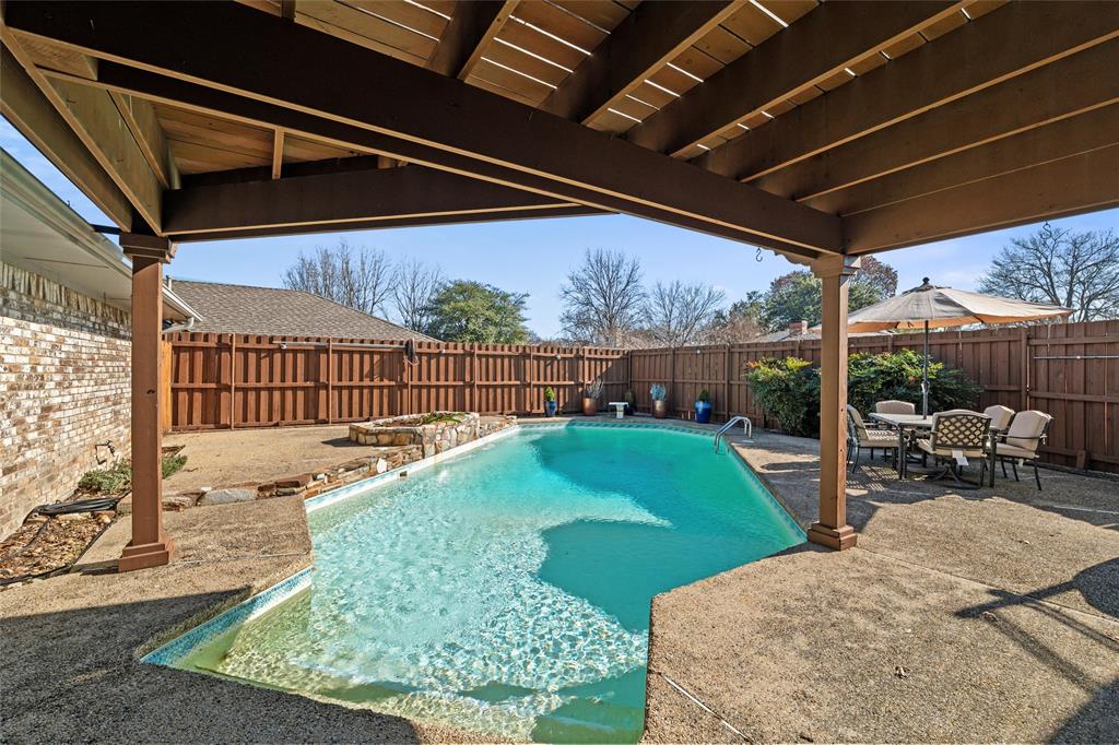 1704 Throwbridge Lane Plano, TX 75023 - Photo 32 of 40 Backyard features an in-ground saltwater pool with concrete pool decking, integrated entry steps, and perimeter safety fencing. Covered patio with wood beam structure provides shaded outdoor space, complemented by an elevated wood deck above with direct access from the home.