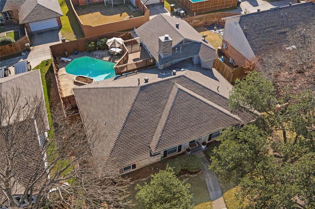 1704 Throwbridge Lane Plano, TX 75023 - Photo 35 of 40 Aerial views show the fenced backyard with a saltwater swimming pool and concrete decking. A raised wood deck is connected to the upstairs room and overlooks the pool area.