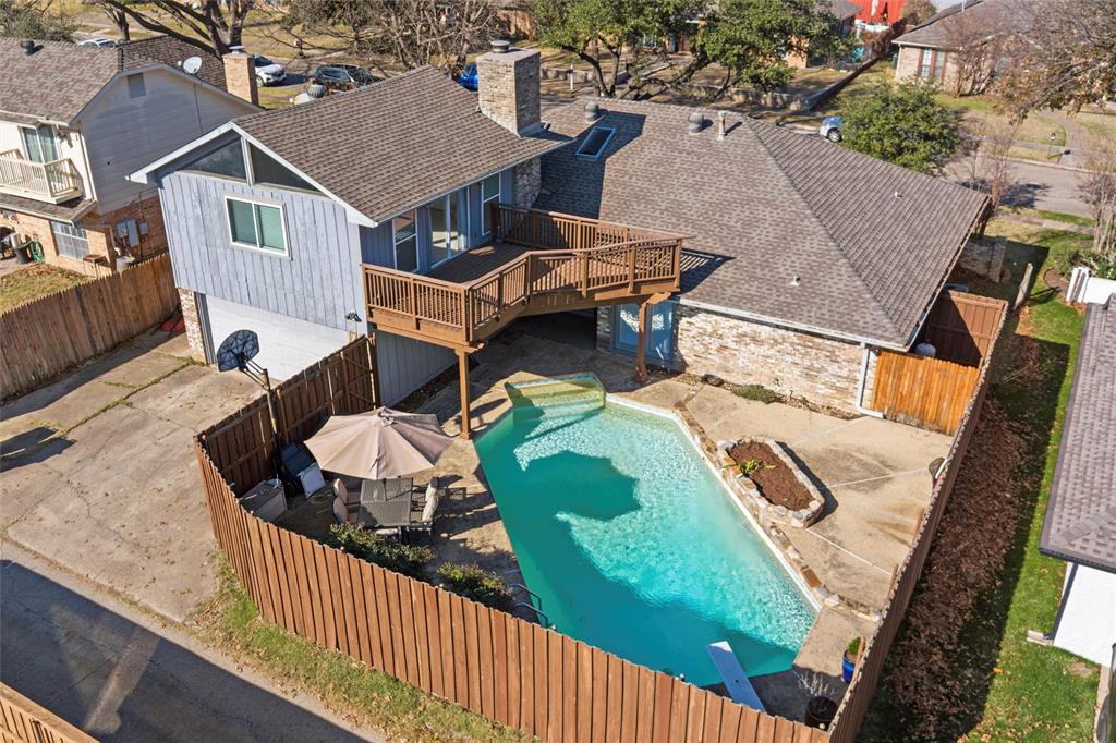 1704 Throwbridge Lane Plano, TX 75023 - Photo 37 of 40 Aerial views show the fenced backyard with a saltwater swimming pool and concrete decking. A raised wood deck is connected to the upstairs room and overlooks the pool area.