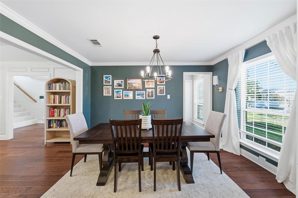 1704 Throwbridge Lane Plano, TX 75023 - Photo 8 of 40 Dining area features smooth ceiling with crown molding and a ceiling-mounted chandelier. Wide cased openings connect the space to adjacent rooms, with large windows allowing natural light and hardwood flooring extending throughout.