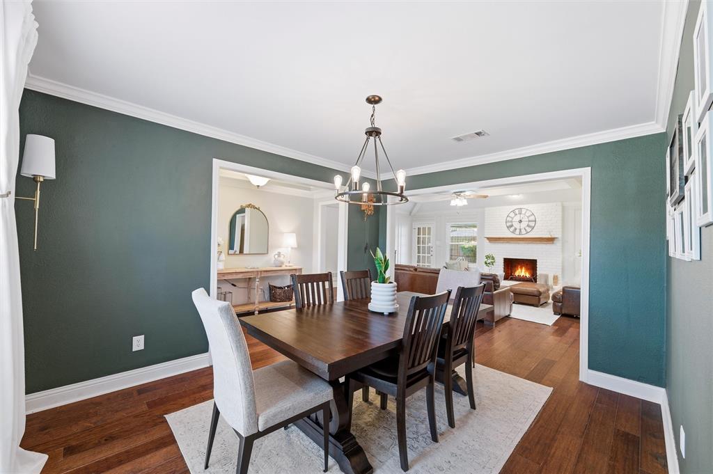1704 Throwbridge Lane Plano, TX 75023 - Photo 10 of 40 Dining area features smooth ceiling with crown molding and a ceiling-mounted chandelier. Wide cased openings connect the space to adjacent rooms, with large windows allowing natural light and hardwood flooring extending throughout.