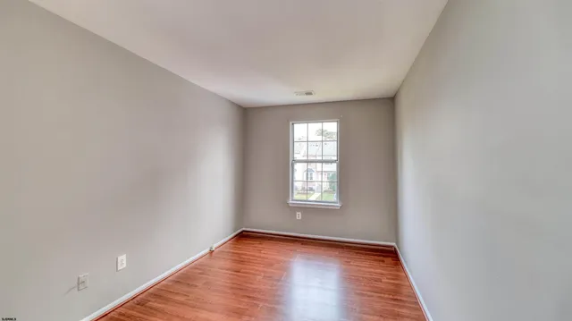 a view of an empty room with wooden floor and window