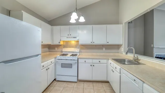 a kitchen with a sink dishwasher a stove and white cabinets