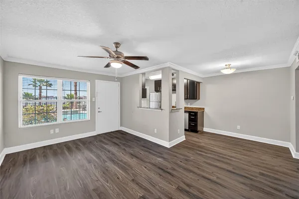 a view of an empty room with a kitchen and wooden floor