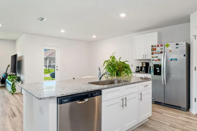a kitchen with stainless steel appliances granite countertop a sink a refrigerator and a counter space