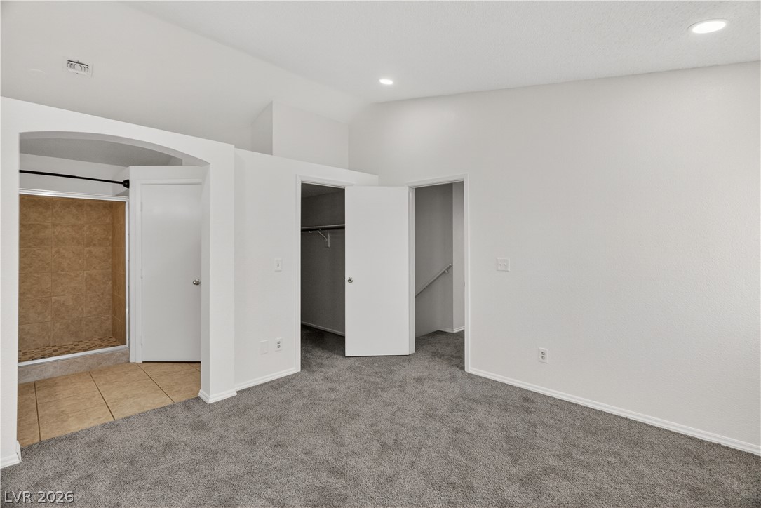 3156 Terrace View Drive Laughlin, NV 89029 - Photo 32 of 94 A well-lit room with plush carpeting, offering convenient access to a walk-in closet and a nearby tiled shower.