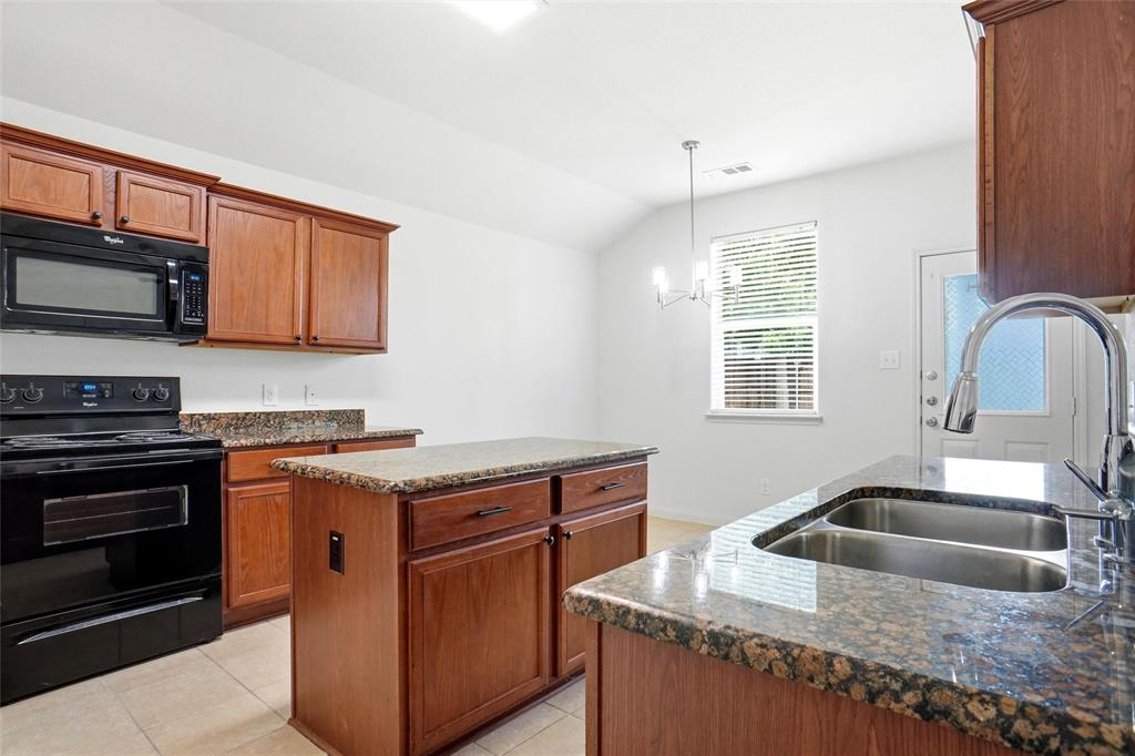 216 Meadow Ridge Drive Anna, TX 75409 - Photo 9 of 16 a kitchen with granite countertop a sink wooden cabinets and stainless steel appliances