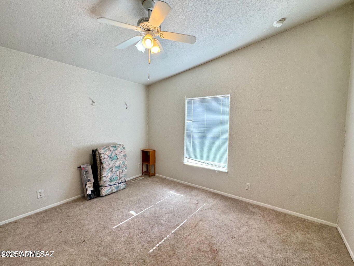 2627 West Hansen Road Willcox, AZ 85643 - Photo 21 of 42 an empty room with windows and fan