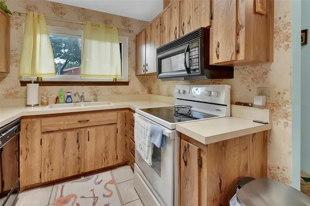 a utility room with stainless steel appliances a stove a sink and a microwave