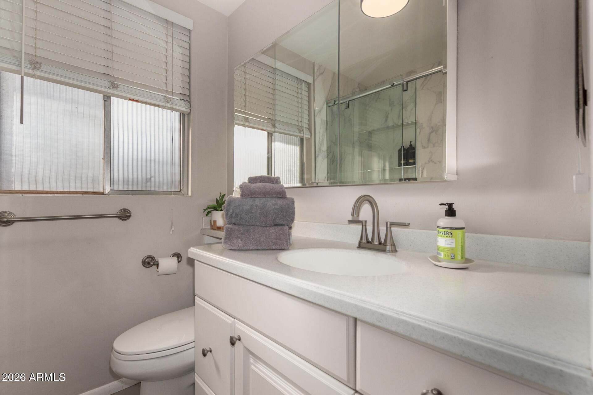 3270 East Camelback Road, Unit 213 Phoenix, AZ 85018 - Photo 23 of 41 a bathroom with a granite countertop sink a toilet and a mirror