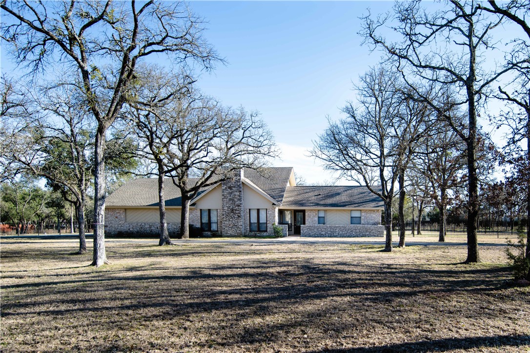 a front view of a house with large trees