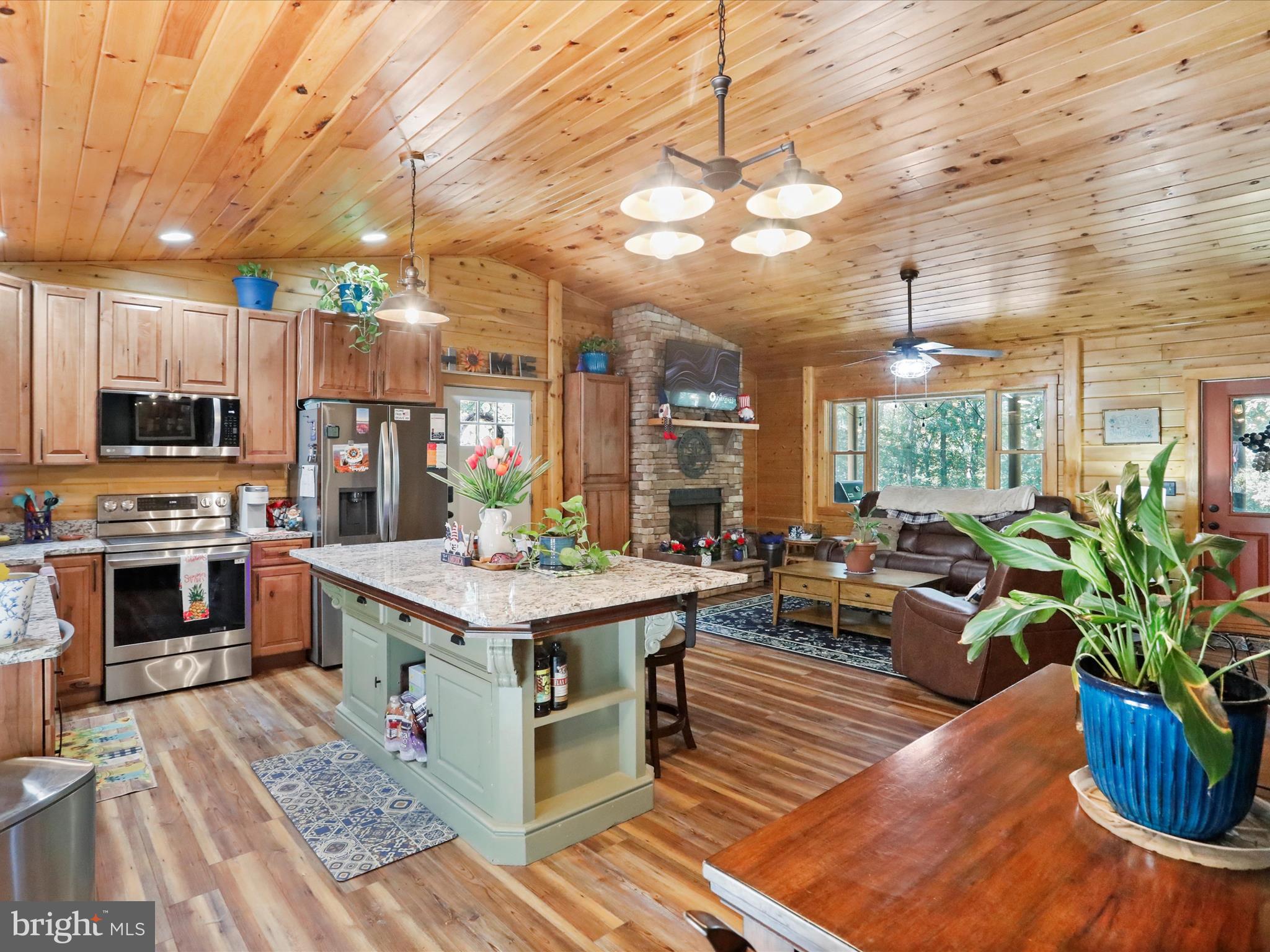 480 High Mountain Road Romney, WV 26757 - Photo 25 of 46 a living room with stainless steel appliances kitchen island granite countertop a table chairs and a wooden floor