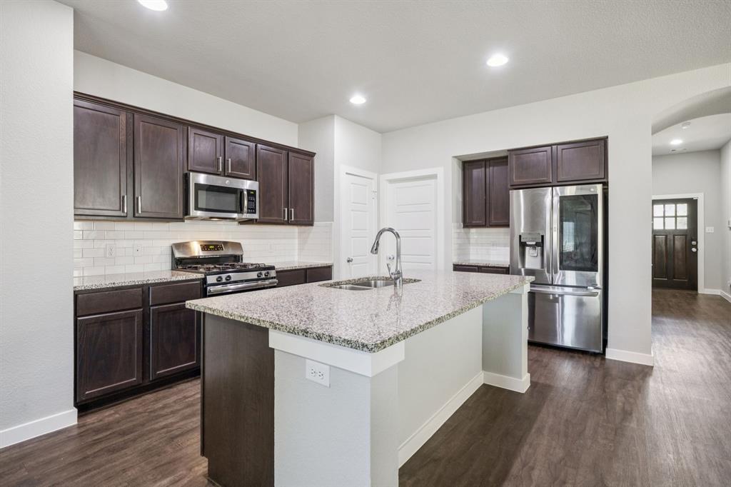 5112 Cathy Drive Forney, TX 75126 - Photo 5 of 32 a kitchen with kitchen island granite countertop stainless steel appliances and wooden cabinets