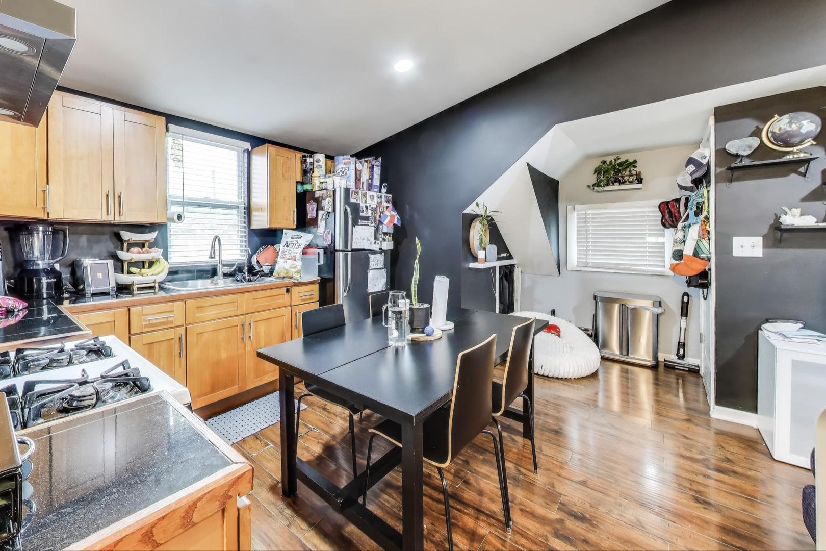 6432 South Kilpatrick Avenue Chicago, IL 60629 - Photo 24 of 36 a kitchen with stainless steel appliances granite countertop a refrigerator a sink dishwasher a stove and a dining table with wooden floor