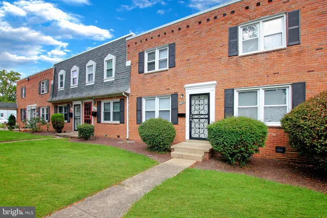 a view of a brick house with a yard and plants