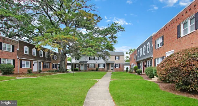 a view of a big yard in front of a brick house with a large tree