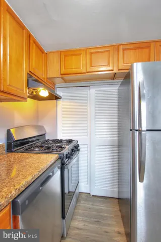a kitchen with stainless steel appliances granite countertop a refrigerator a stove and a sink