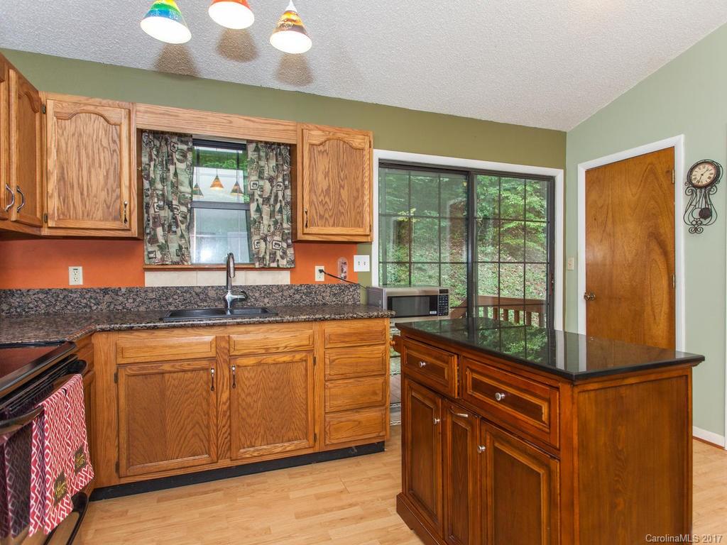 99 Apgar Road Candler, NC 28715 - Photo 5 of 20 a kitchen with granite countertop a sink and wooden cabinets