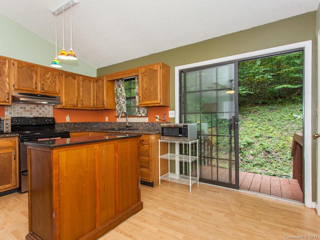 99 Apgar Road Candler, NC 28715 - Photo 6 of 20 a kitchen with stainless steel appliances granite countertop a refrigerator a sink dishwasher a stove and a dining table with wooden floor
