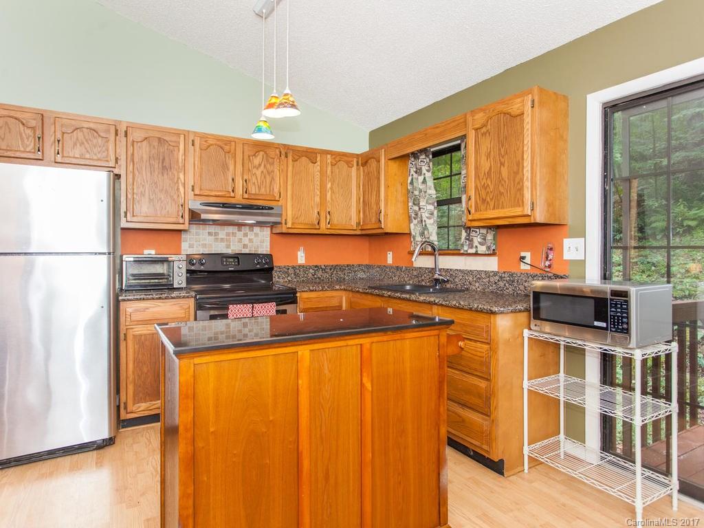 99 Apgar Road Candler, NC 28715 - Photo 7 of 20 a kitchen with stainless steel appliances granite countertop a refrigerator a sink a stove and white cabinets with wooden floor