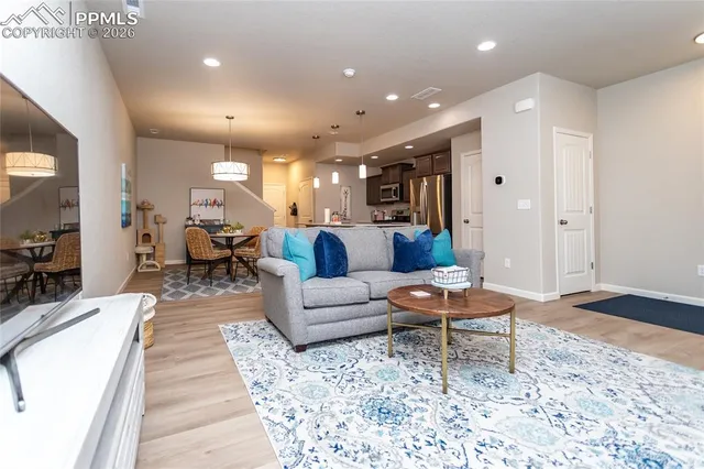 a living room with furniture and a dining table with wooden floor