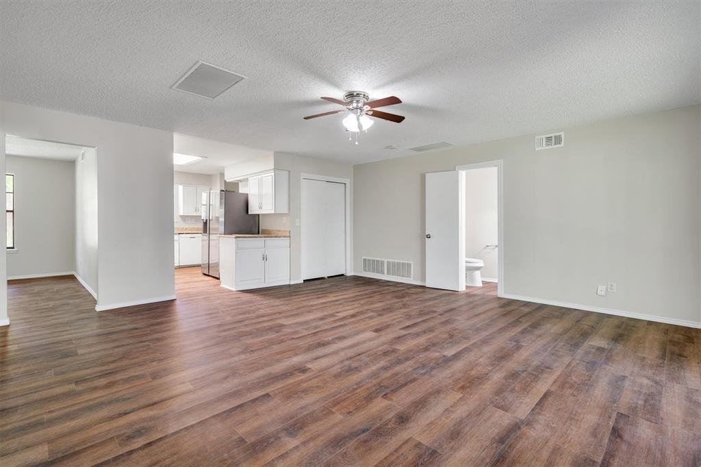 209 Mistletoe Lane Keene, TX 76059 - Photo 9 of 38 a view of an empty room with wooden floor and a ceiling fan