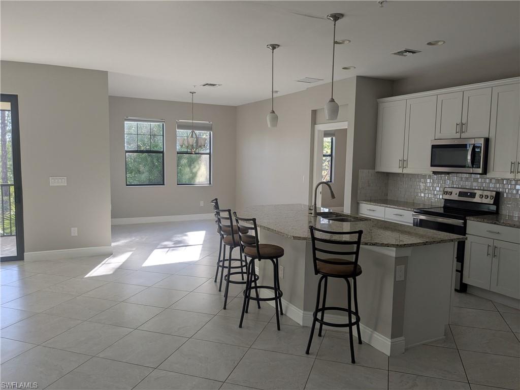 15188 Butler Lake Drive, Unit 202 Naples, FL 34109 - Photo 2 of 5 a kitchen with stainless steel appliances a stove a sink refrigerator and a microwave