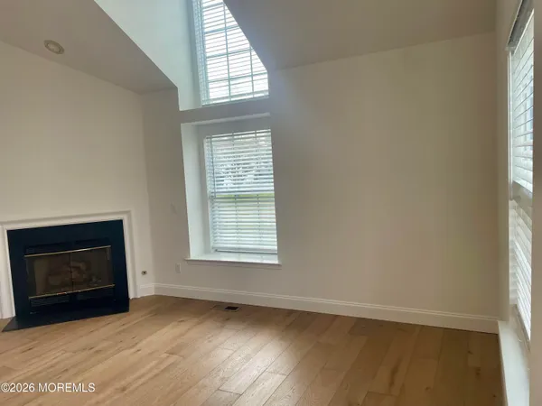 an empty room with wooden floor fireplace and windows
