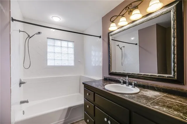 a bathroom with a granite countertop sink mirror and a bathtub