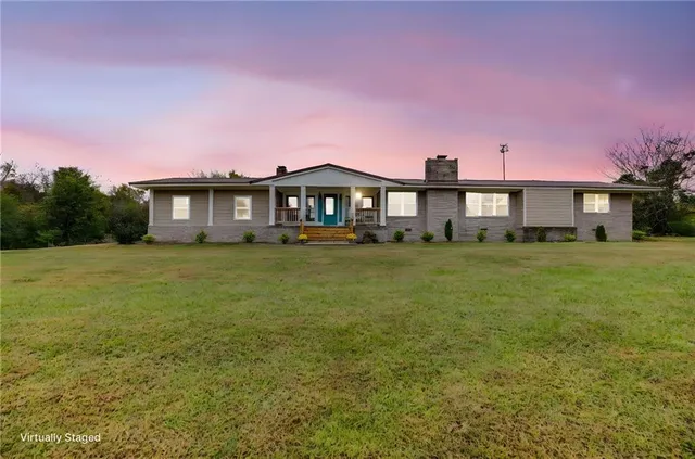 a front view of a house with a yard and trees