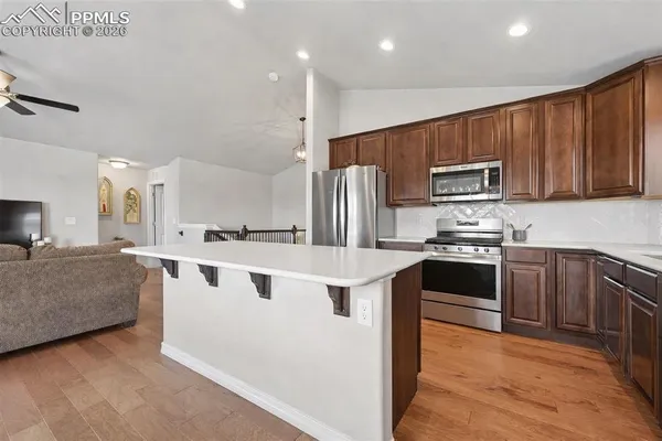 a kitchen with stainless steel appliances kitchen island granite countertop a stove a sink and a refrigerator