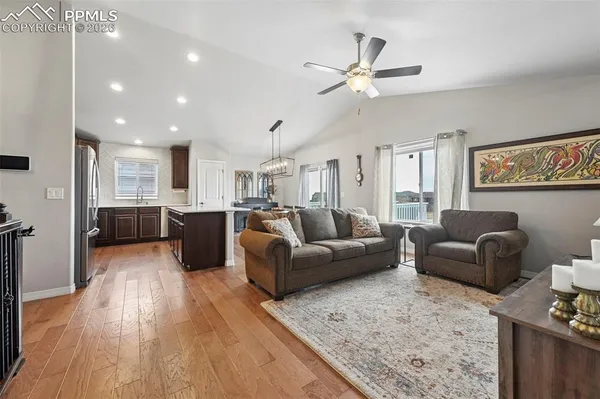 a living room with furniture kitchen view and a wooden floor