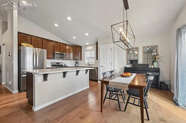 a kitchen with stainless steel appliances a dining table chairs refrigerator and cabinets