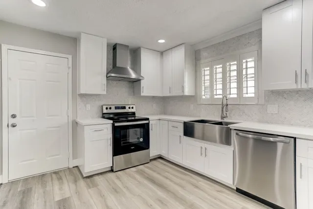 a kitchen with white cabinets and stainless steel appliances