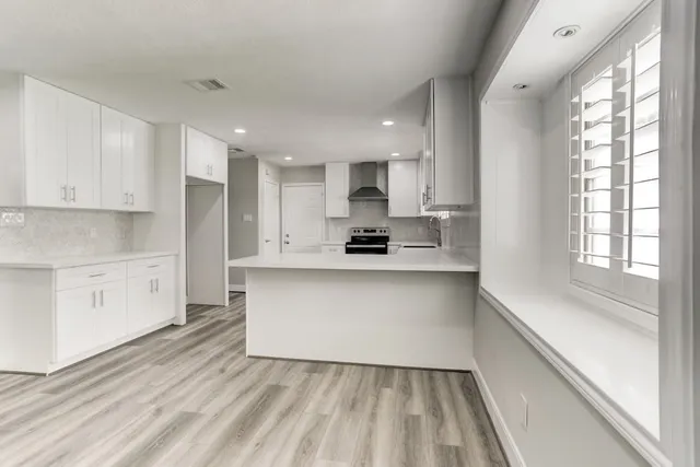a open kitchen with white cabinets and a window