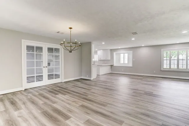 an empty room with windows and wooden floor