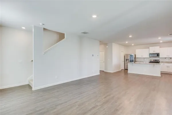 a kitchen with stainless steel appliances granite countertop a sink a microwave a refrigerator and white cabinets