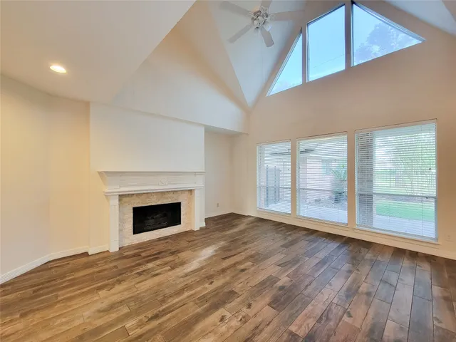 a view of an empty room with wooden floor fireplace and a window