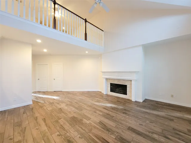 a view of an empty room with wooden floor fireplace and a window