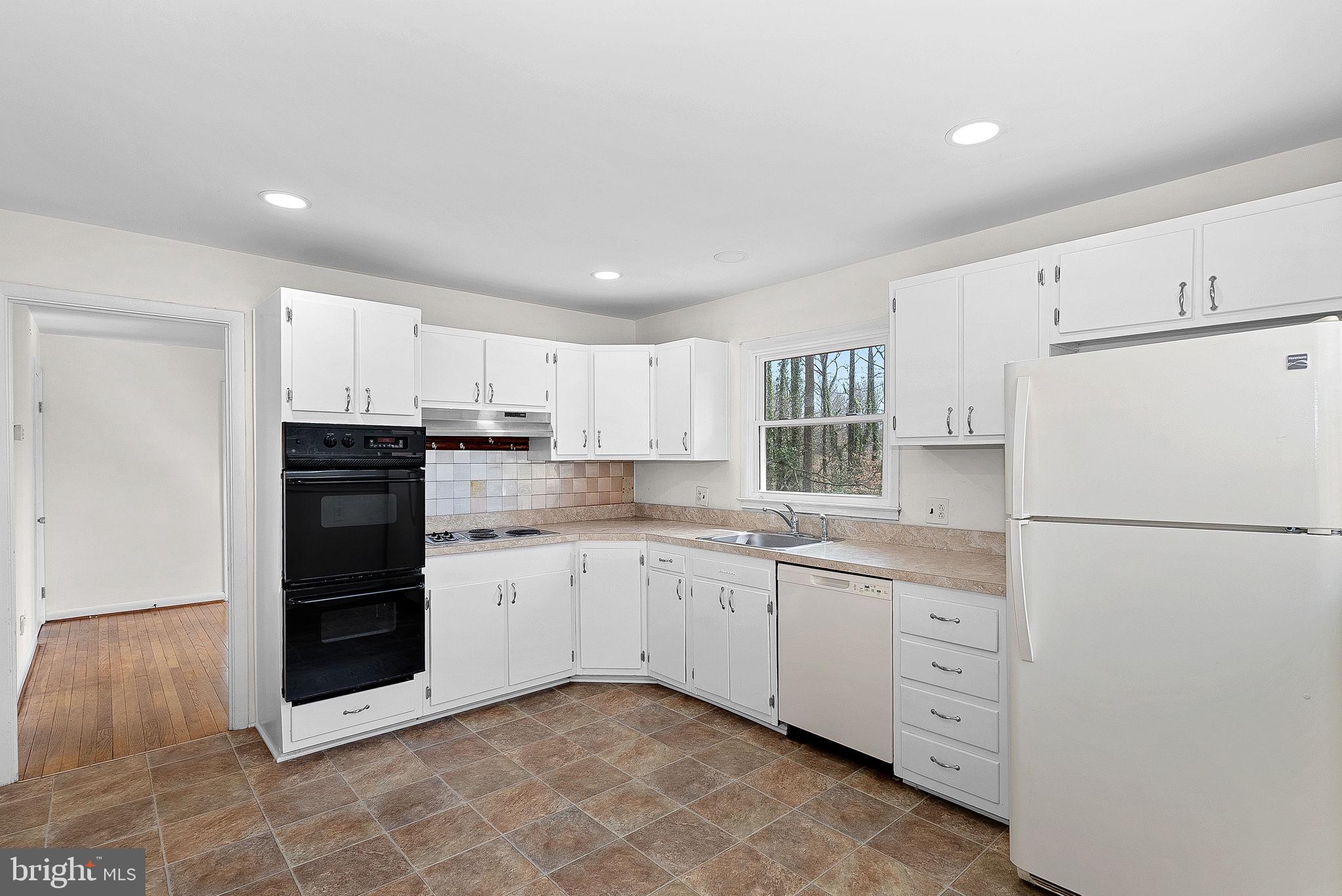 10021 Glenmere Road Fairfax, VA 22032 - Photo 11 of 45 a kitchen with granite countertop a refrigerator sink and white cabinets